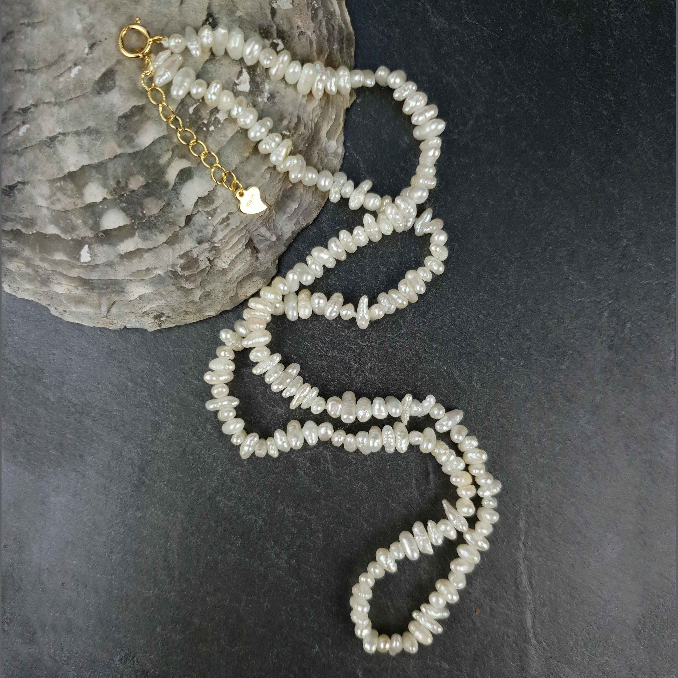 Zoetwater parelketting met kleine witte parels liggend op leisteen | Mily