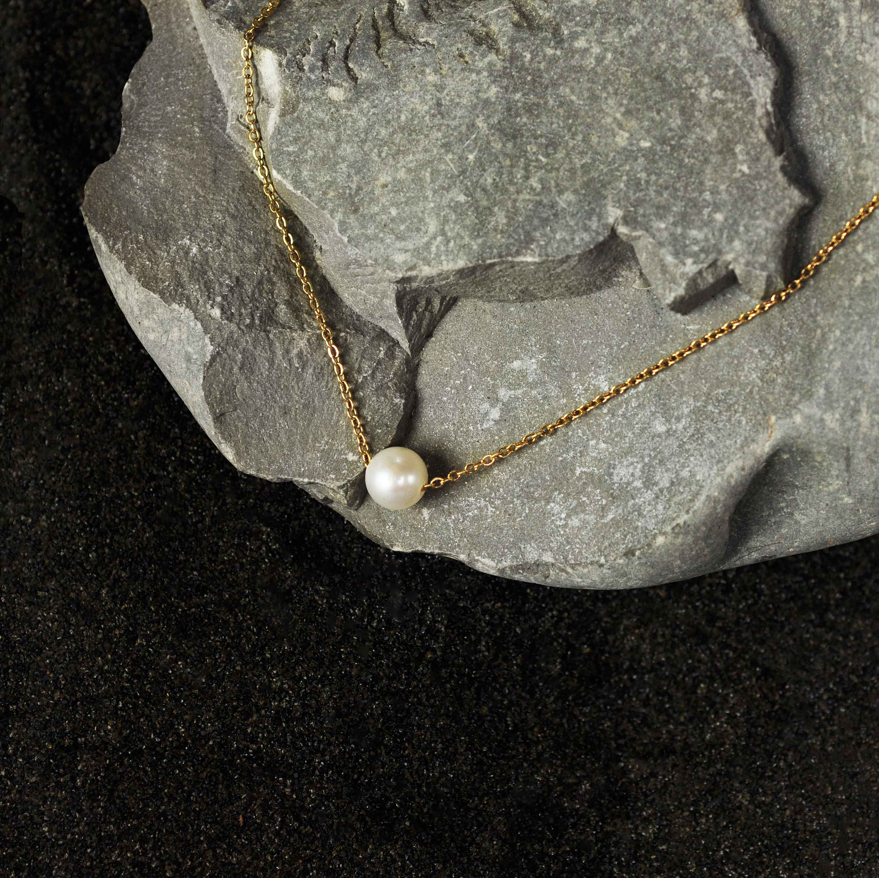 Zoetwater parelketting met witte parel aan goud edelstalen ketting liggend op grijze steen | Single One Pearl Gold