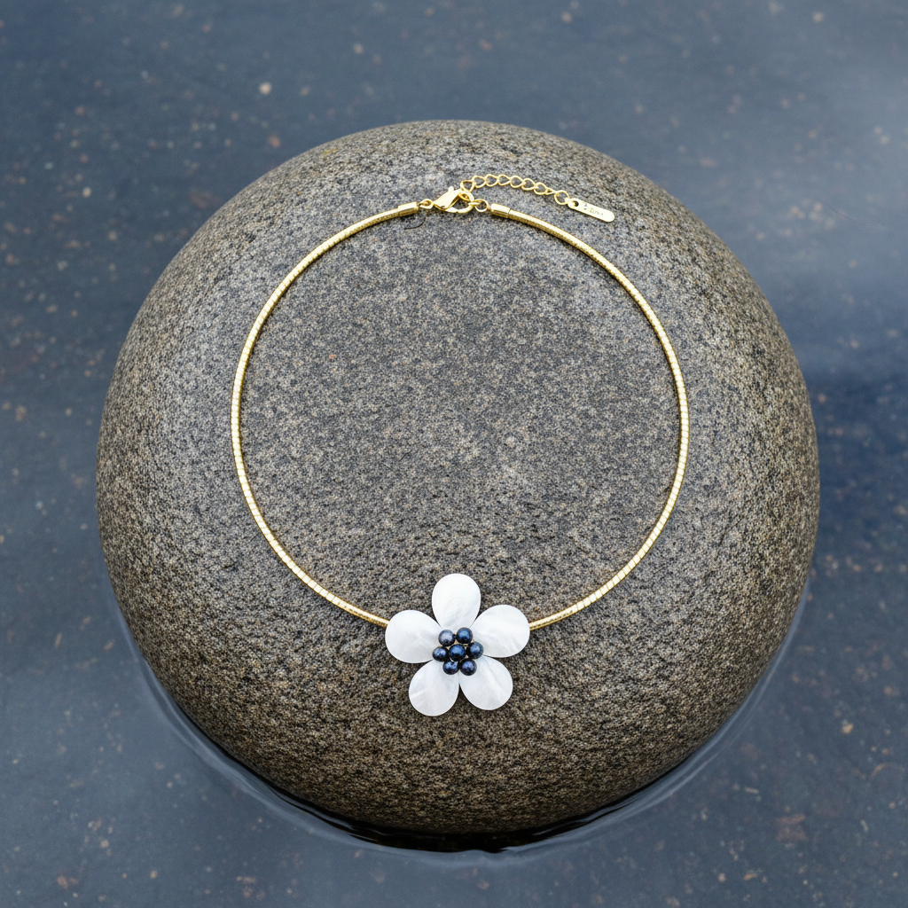 Zoetwater parelketting met parelmoeren bloem aan goud edelstalen ketting liggend op steen | set Fleury B Gold