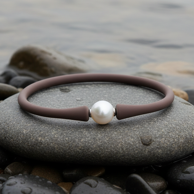 Wit elastisch parel armband met bruine band liggend op steen in water | Browly