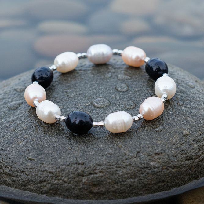 Zoetwater parel armband met witte, grijze en zalm kleurige parels liggend op natte steen | Marlotte