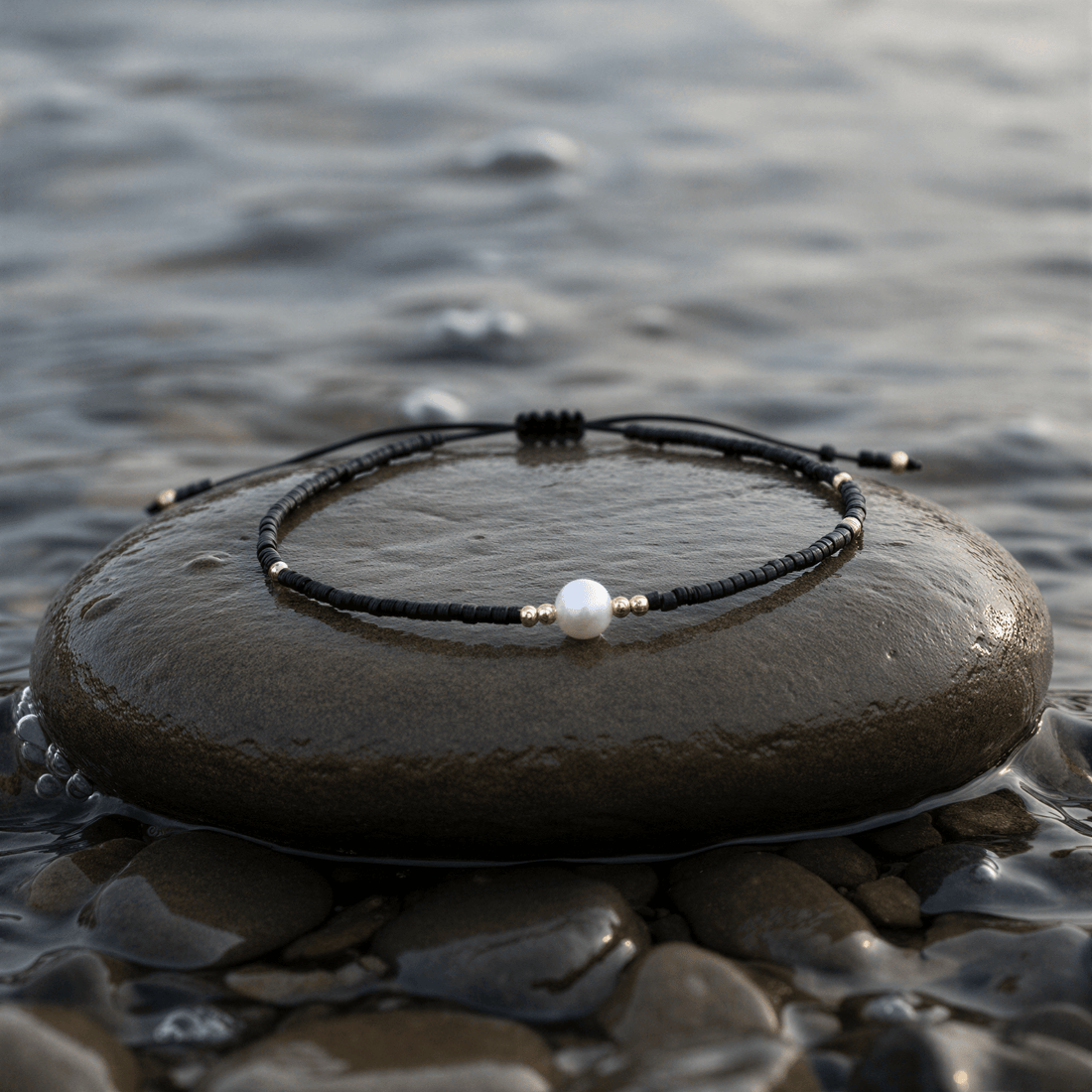 Wit zoetwater parelarmband met zwarte kraaltjes liggend op steen in water | Mini Pearl One Black Color