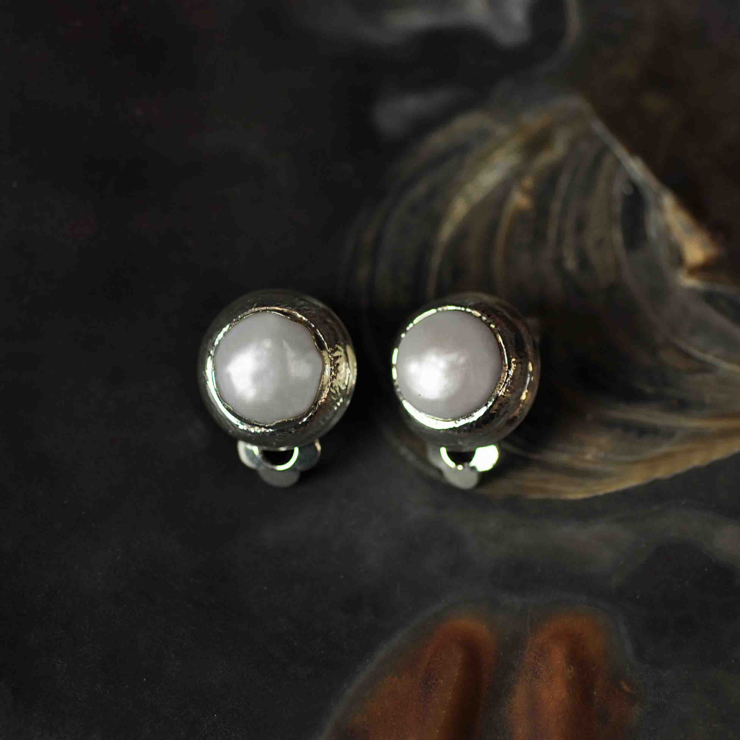 Witte zoetwater parel clips oorbellen met zilveren rand liggend in schelp vooraanzicht | One Silver Clip Pearl