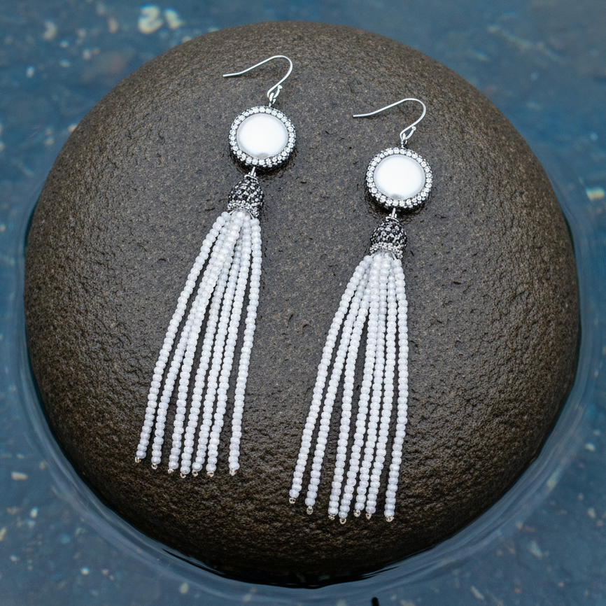 Lange witte parel oorbellen met stras steentjes en sterling zilver (925) liggend op steen | Bright Coin Pearl White Crystal Tassel