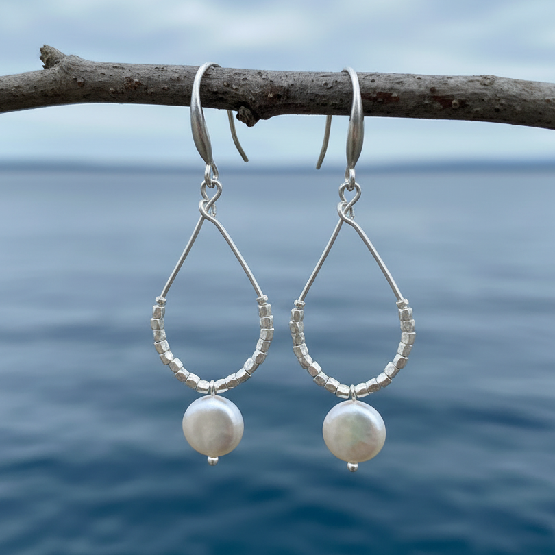 Lange witte zoetwater parel oorbellen met witte coin parel en mat zilver hangend aan takje | Milany Silver