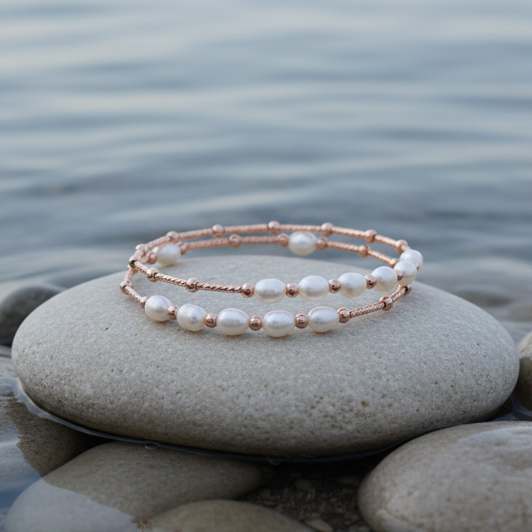 Zoetwater parel wikkel armband met witte parels en rose goud liggend op steen in water | Wrap Rose White Pearl