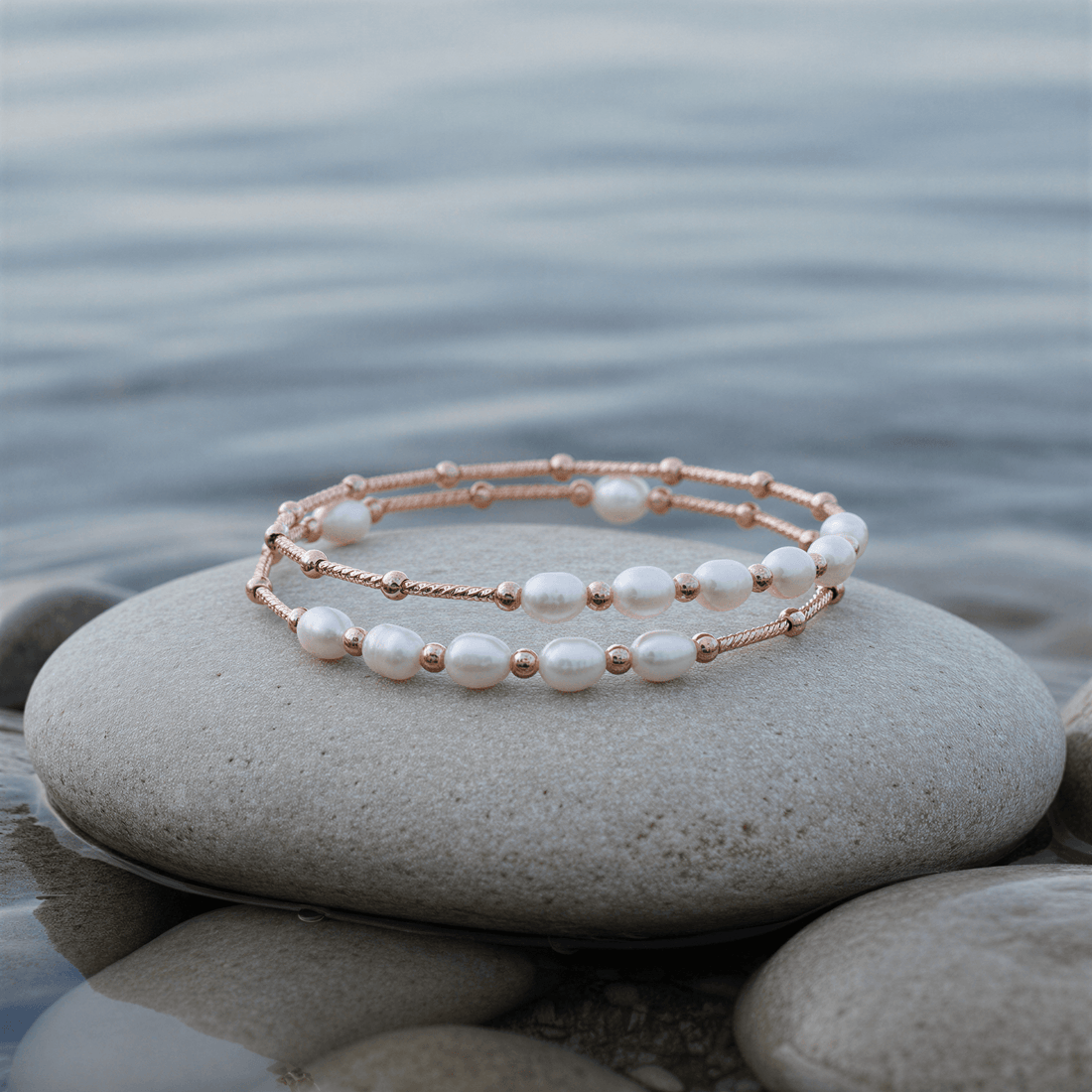 Zoetwater parel wikkel armband met witte parels en rose goud liggend op steen in water | Wrap Rose White Pearl