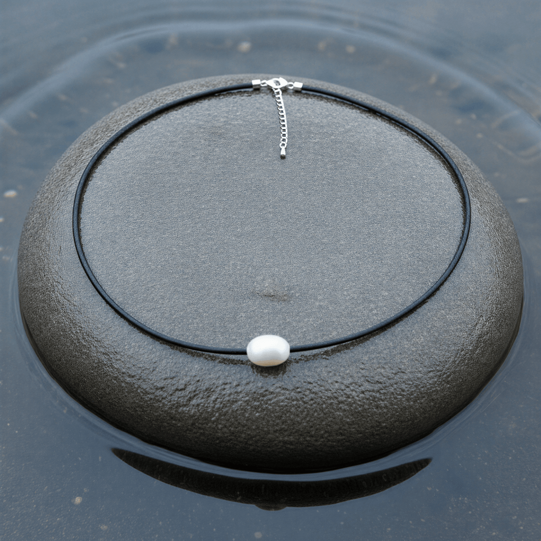 Wit zoetwater parelketting met zwart leer en zilver edelstaal liggend op steen in water | Black Leather Pearl White