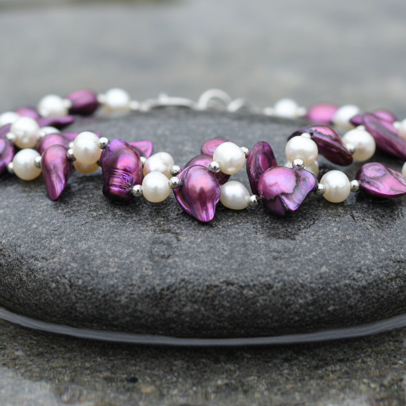 Zoetwater parelketting met witte en paarse parels in 2 rijen liggend op steen in water met close up | Pia