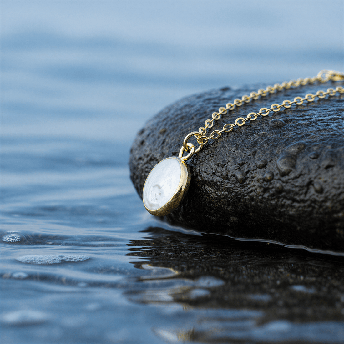 Detail van witte zoetwater parelketting met hanger liggend op steen in water | White Coin Pearl Gold Small