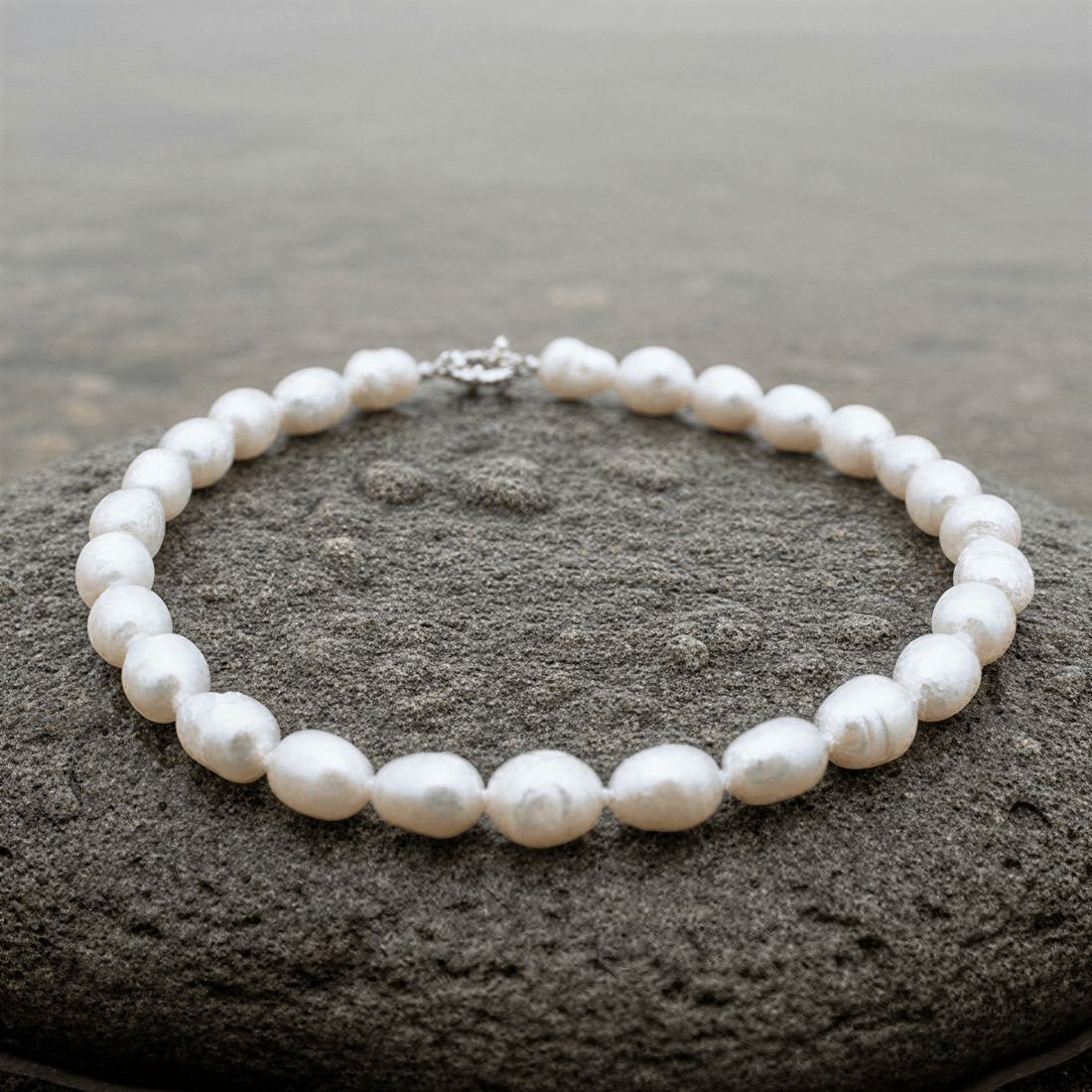 Handgeknoopte witte zoetwater parelketting liggend op natte steen | Wola Two