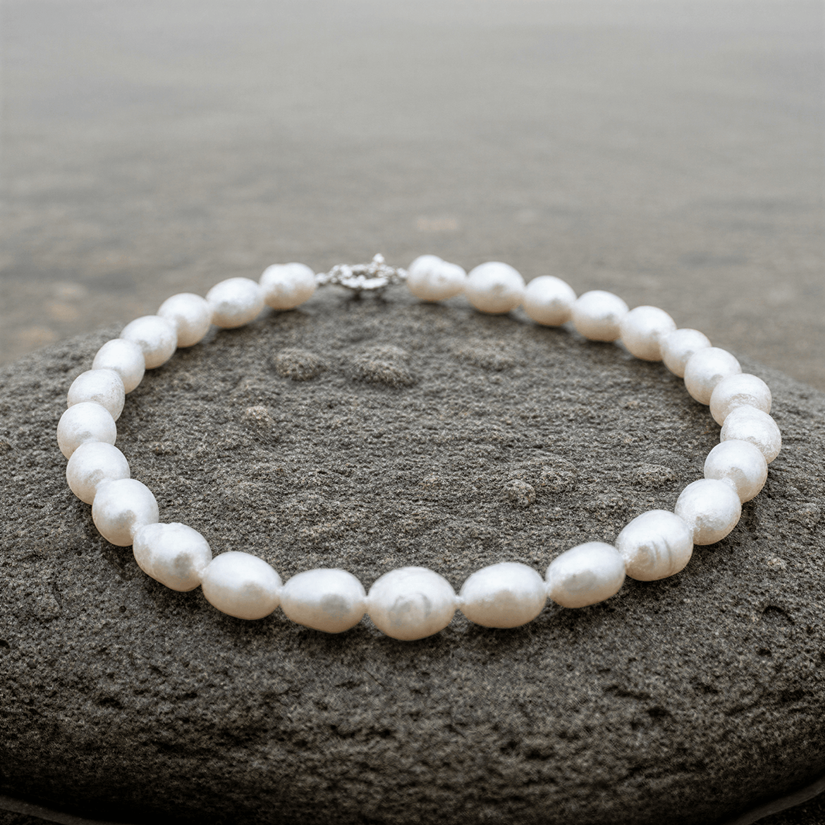 Handgeknoopte witte zoetwater parelketting liggend op natte steen | Wola Two