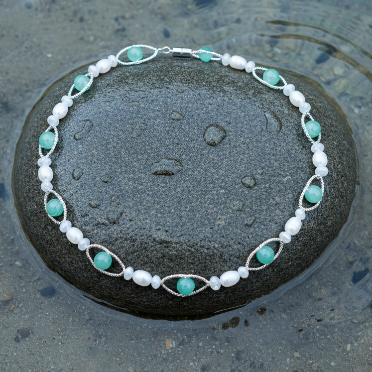 Zoetwater parelketting met witte parels, groene en transparante glaskristallen met magneetslot liggend op steen in water| Janta