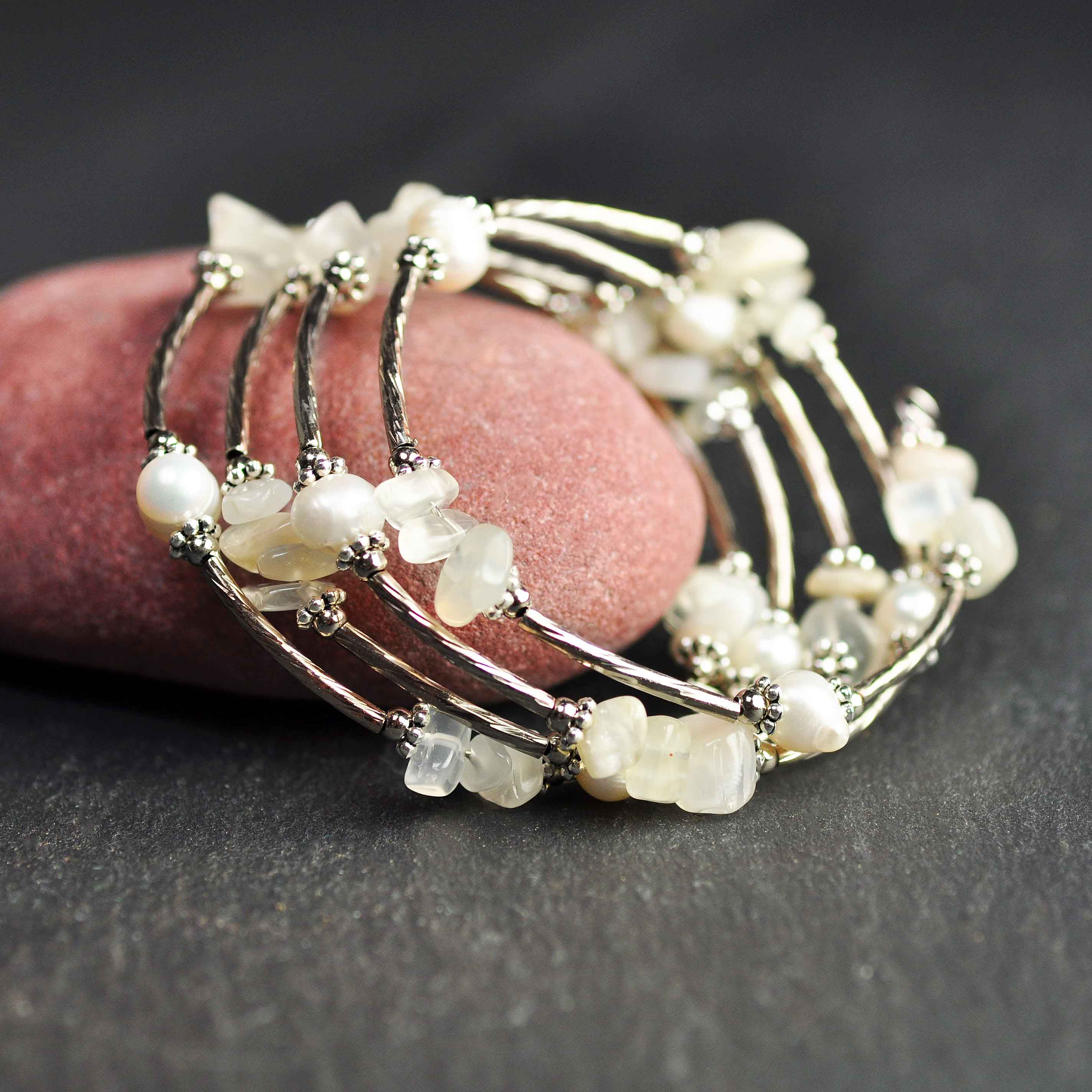 Wit zoetwater parel wikkelarmband met edelsteen maansteen en zilver liggend tegen rode steen | Wrap Pearl Moonstone