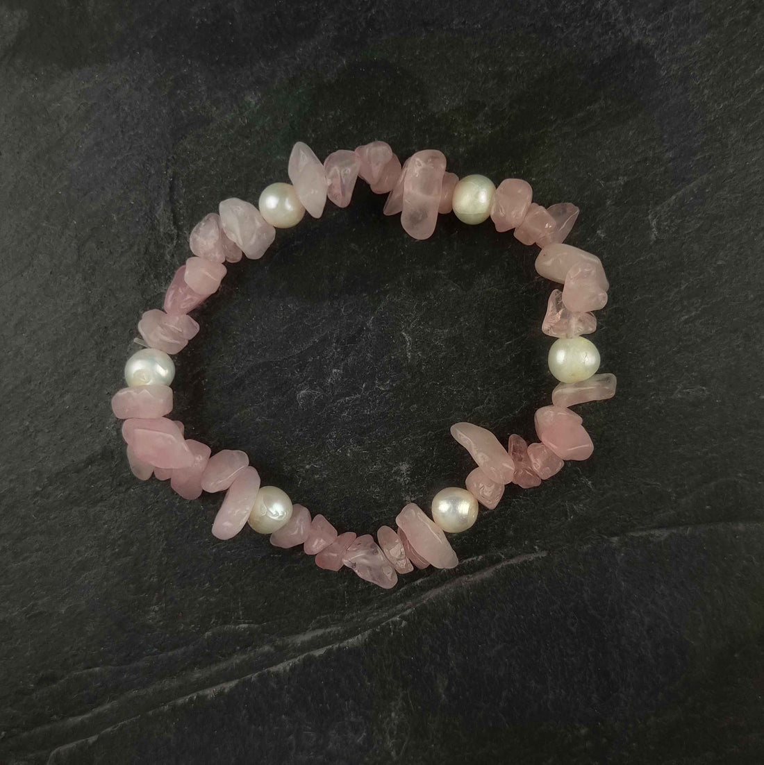 Wit zoetwater parel armband met roze edelstenen rozenkwart bovenaanzicht liggend op leisteen, elastisch | Pearl Rose Quartz Chip