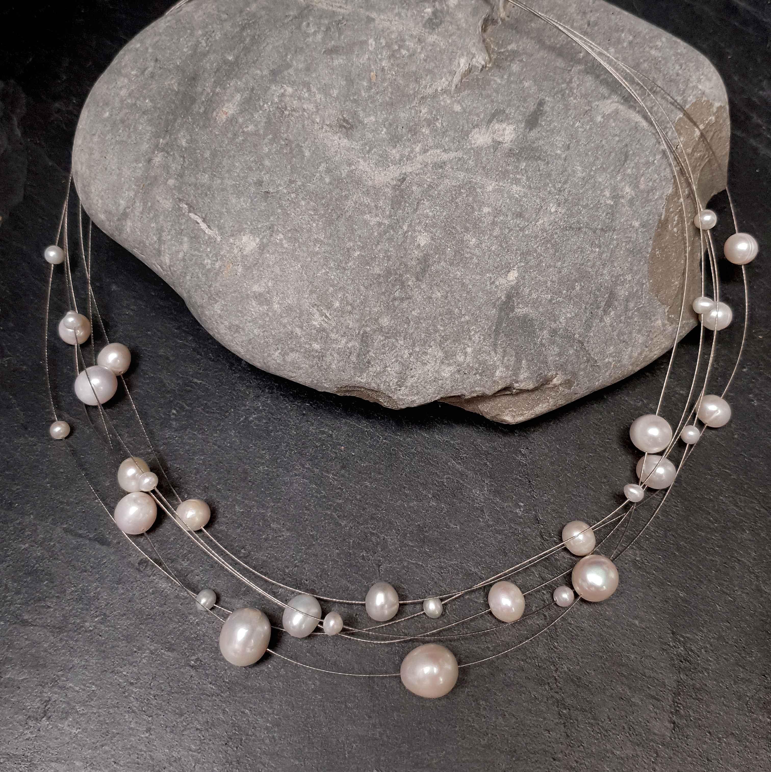 Zoetwater parelketting met witte parels en sterling zilver in 5 rijen liggend op steen | Avetta