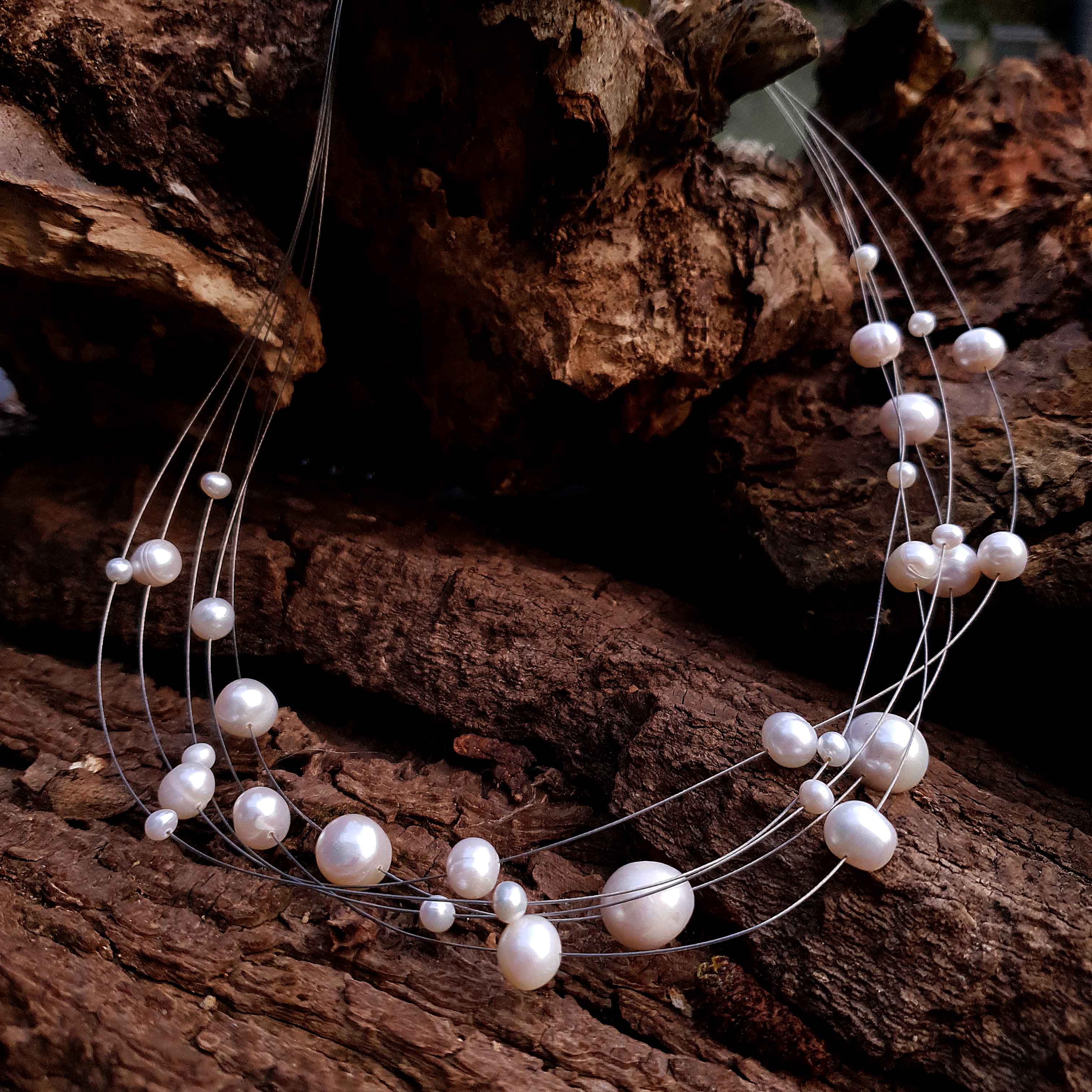 Zoetwater parelketting met witte parels en sterling zilver in 5 rijen liggend op hout | Avetta