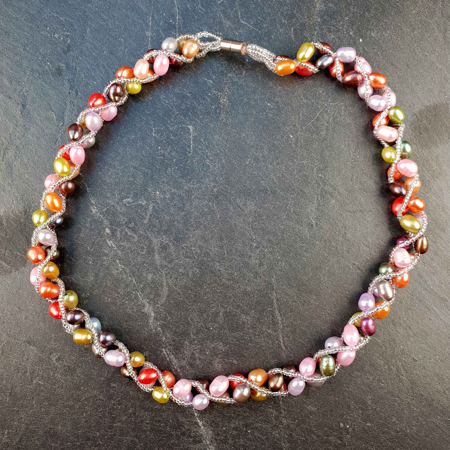 Zoetwater parelketting met vrolijk gekleurde parels en magneetslotje liggend op leisteen | Bonica