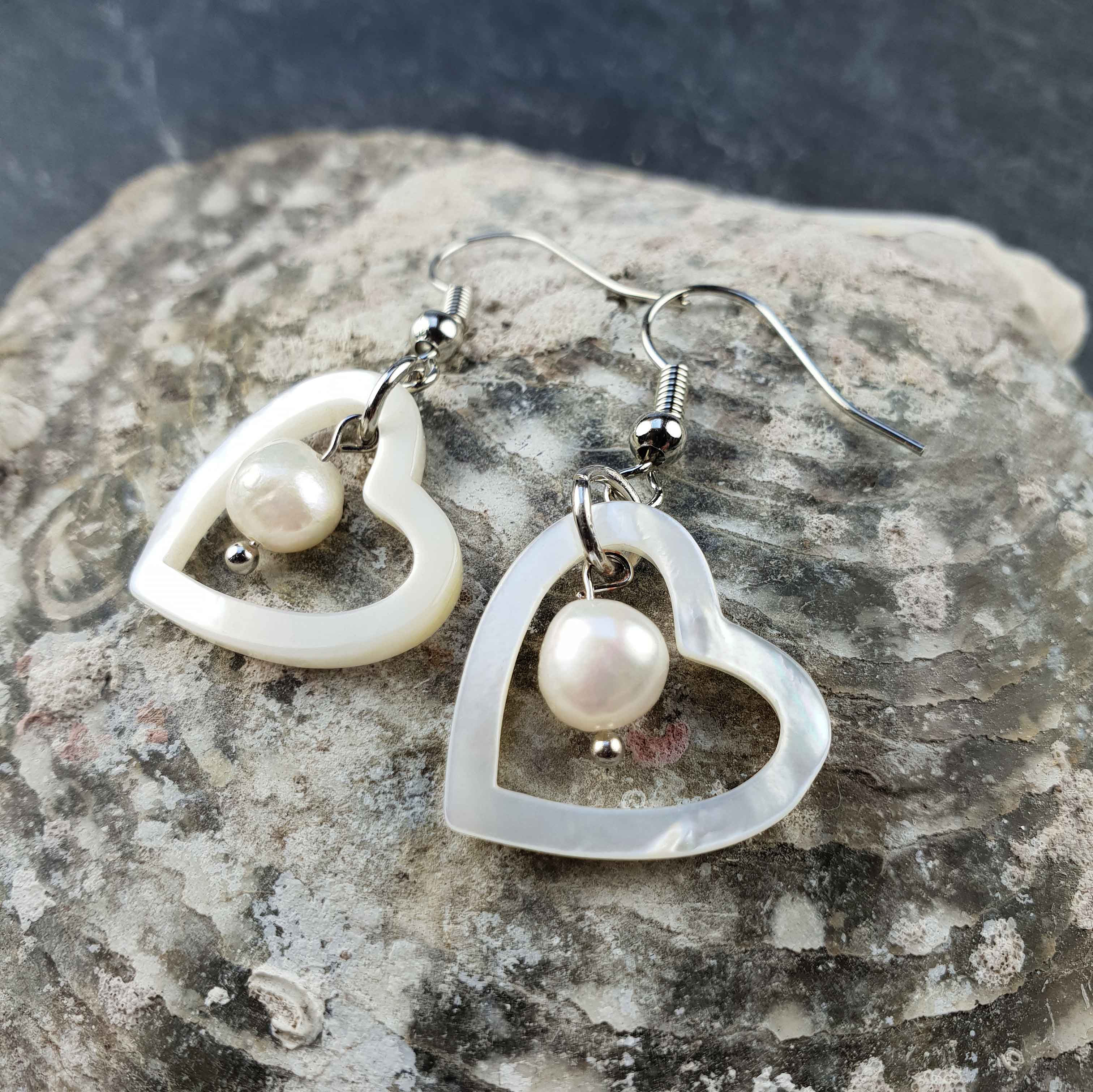 Witte zoetwater parel oorbellen met witte parel en parelmoer hart en sterling zilver (925) liggend op schelp | Pearl Heart Shell