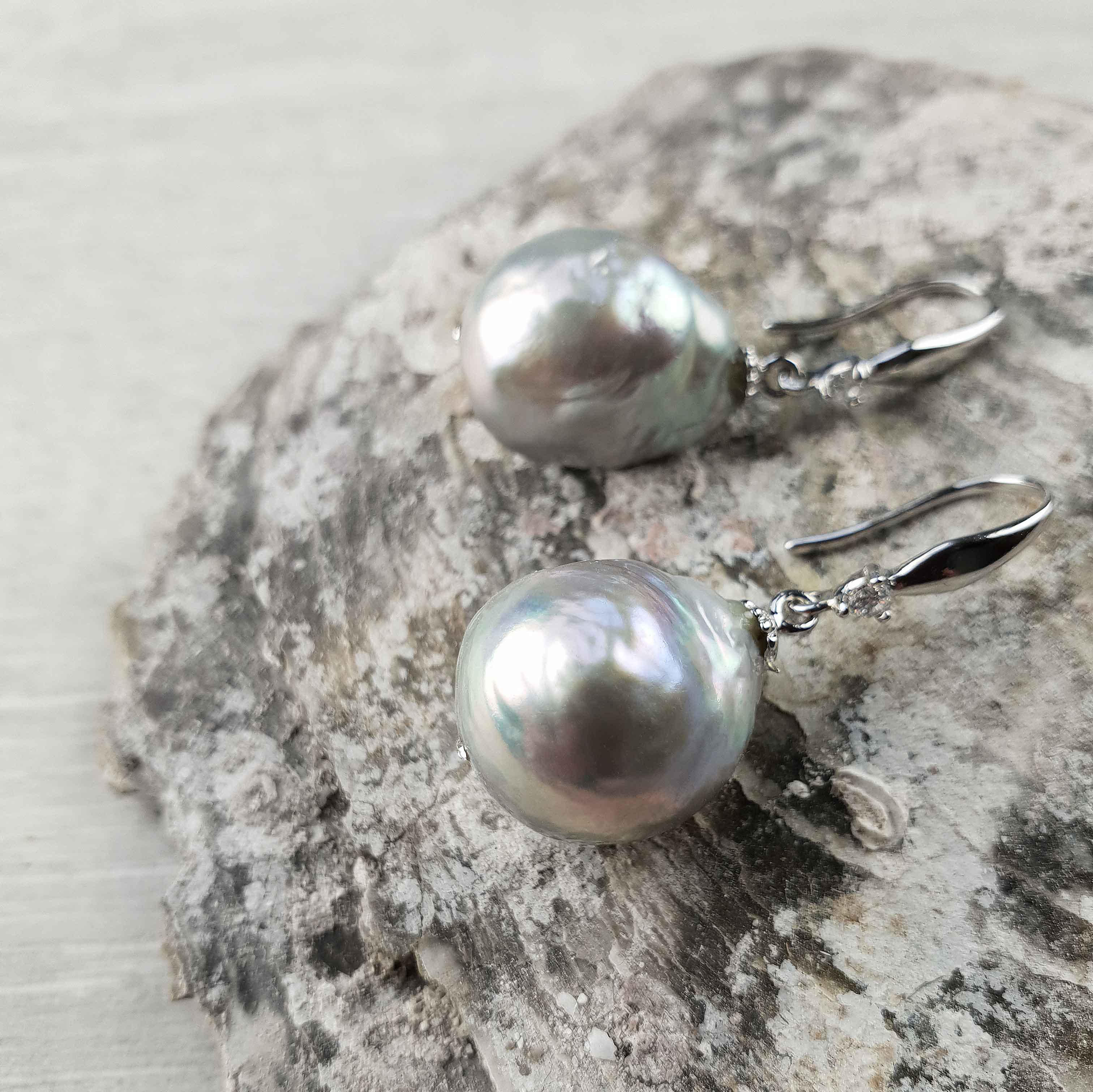 Grijze zoetwater parel oorbellen met sterling zilveren oorbelhaakjes en stras steentje liggend op steen | Bling Kasumi Grey Pearl