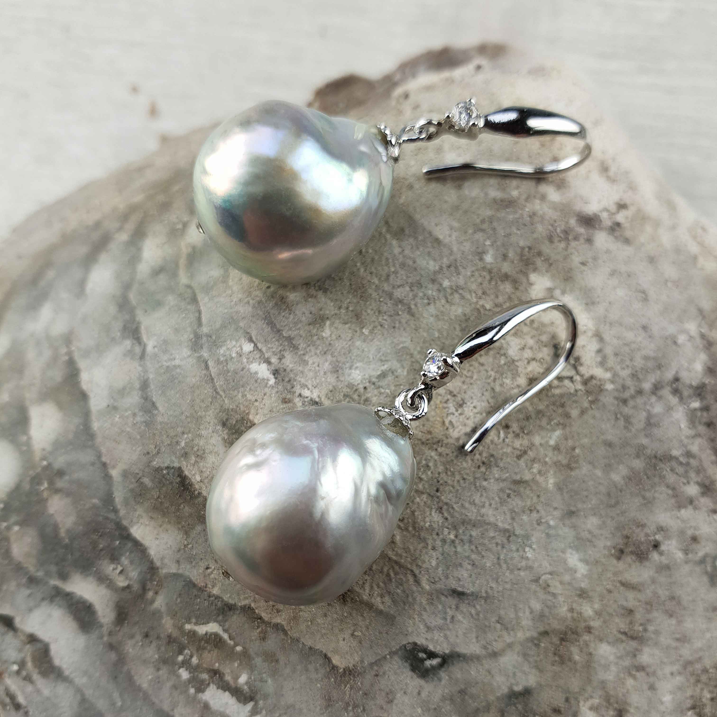 Grijze zoetwater parel oorbellen met sterling zilveren oorbelhaakjes en stras steentje liggend op schelp | Bling Kasumi Grey Pearl