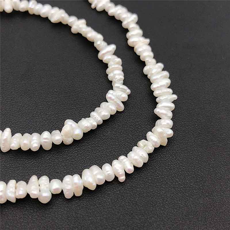 Zoetwater parelketting met kleine witte parels liggend op zwart leer | Mily