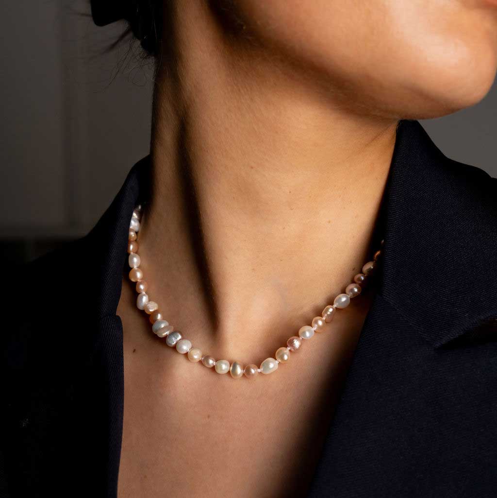 Handgeknoopte zoetwater parelketting met witte, zalm en roze parels en sterling zilver (925) op model met zwart jasje | Pearl Soft Colors Small