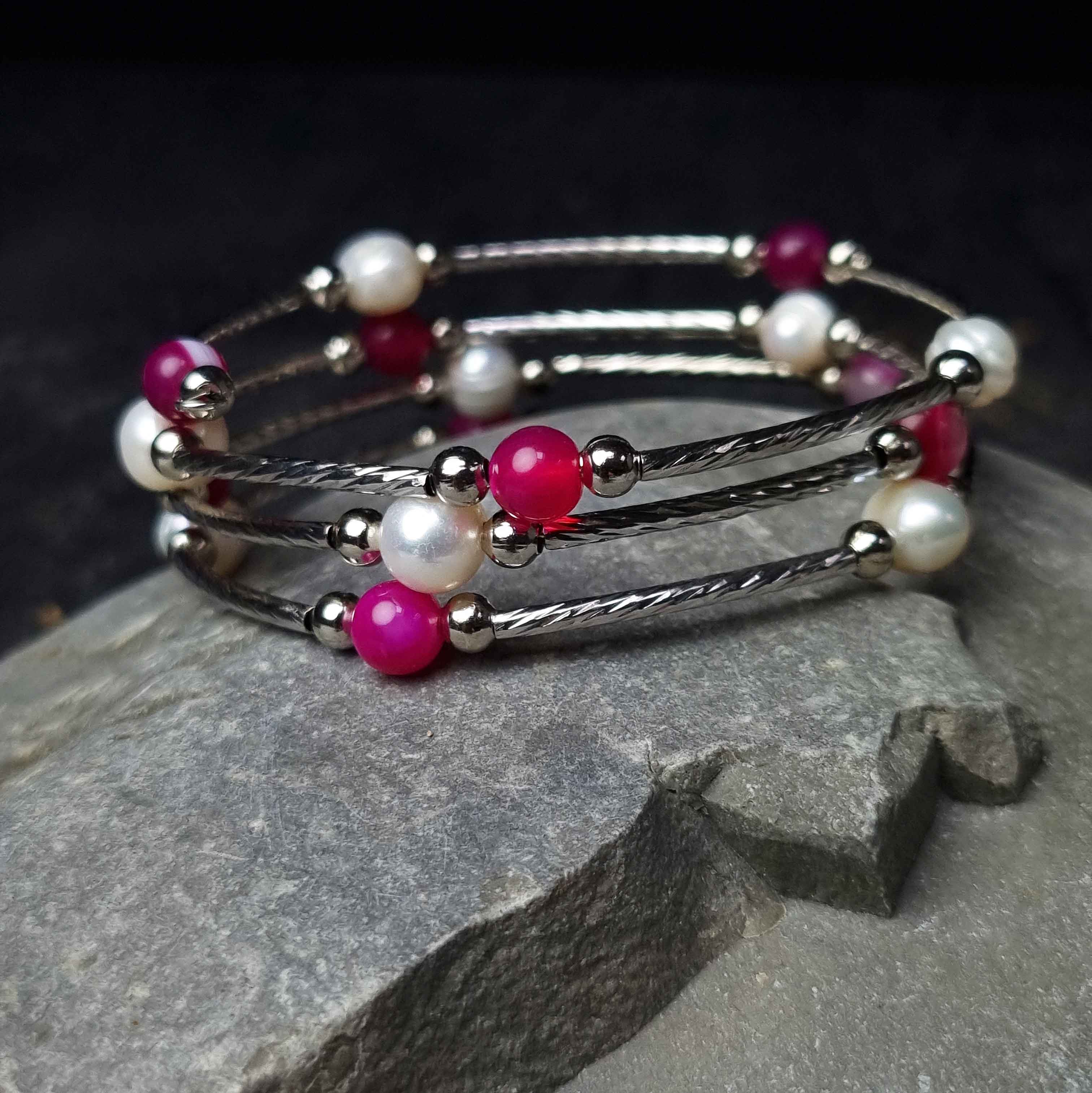 Witte zoetwater parel wikkelarmband met roze edelstenen liggend op steen | Wrap Pearl Pink Striped Agate