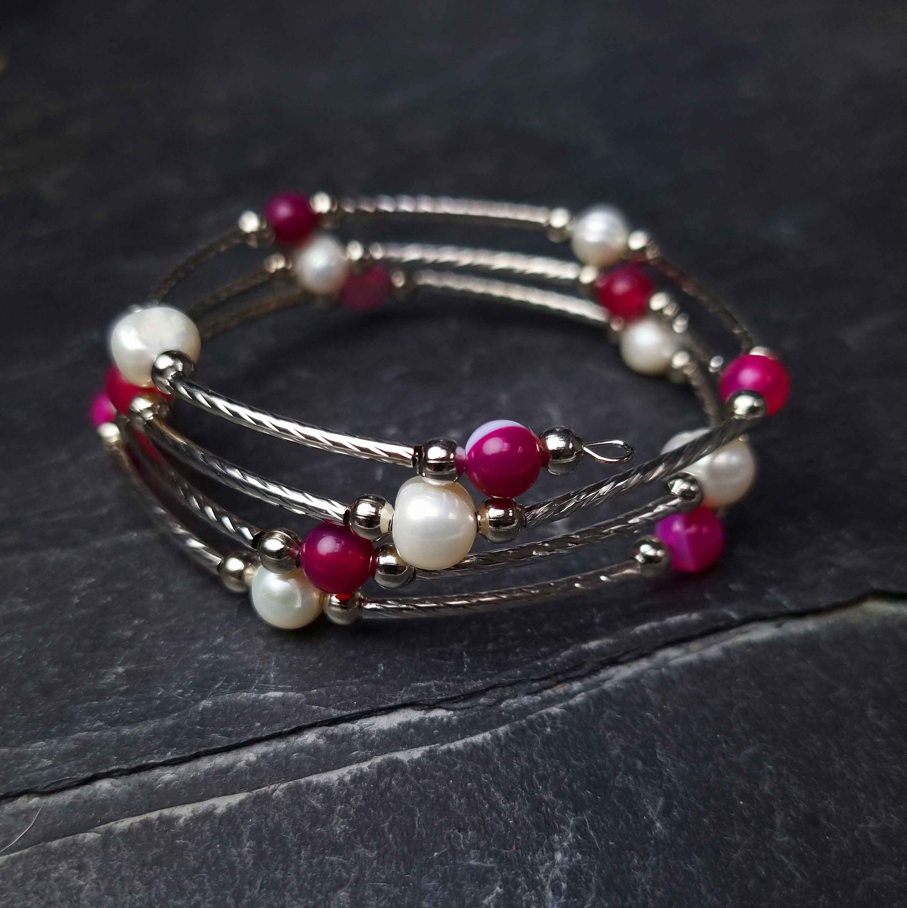 Witte zoetwater parel wikkelarmband met roze edelstenen liggend op leisteen | Wrap Pearl Pink Striped Agate