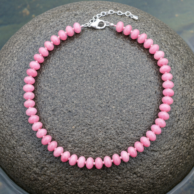 Donker roze handgeknoopte edelstenen ketting met sterling zilver (925) liggend op steen in water | Cherry Quartz Rondelle