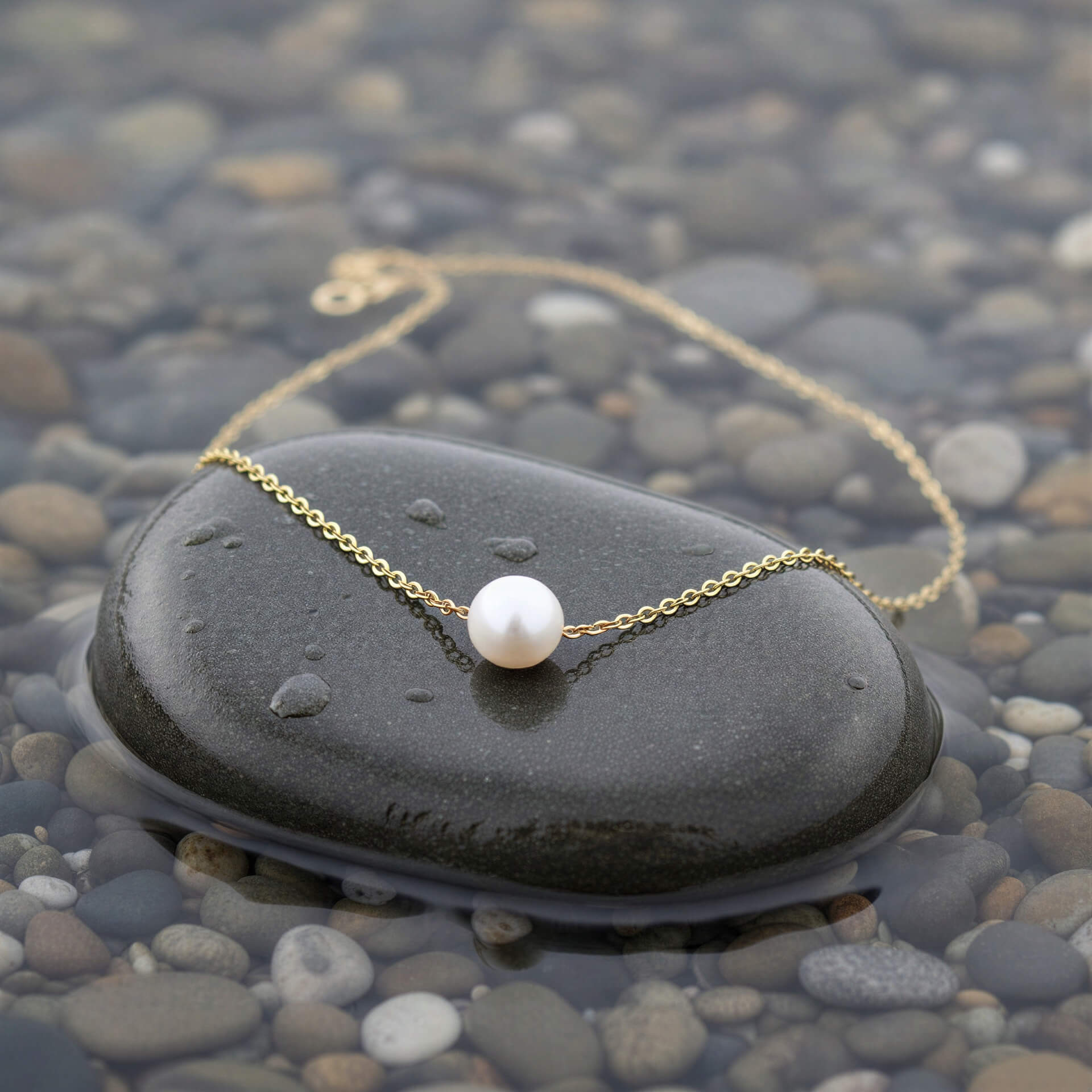 Zoetwater parelketting met witte parel aan goud edelstalen ketting liggend op kei in water | Single One Pearl Gold