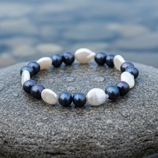 Zoetwater parel armband met witte en blauw zwarte parels liggend op natte steen, elastisch | White Coin Dark Pearl