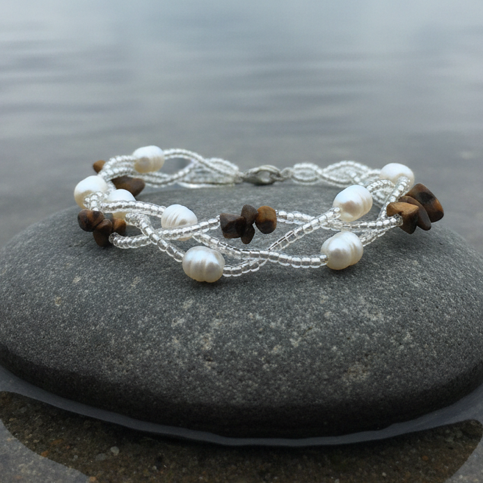 Zoetwater parel met edelstenen armband Twine Pearl Tiger Eye op steen aan het water