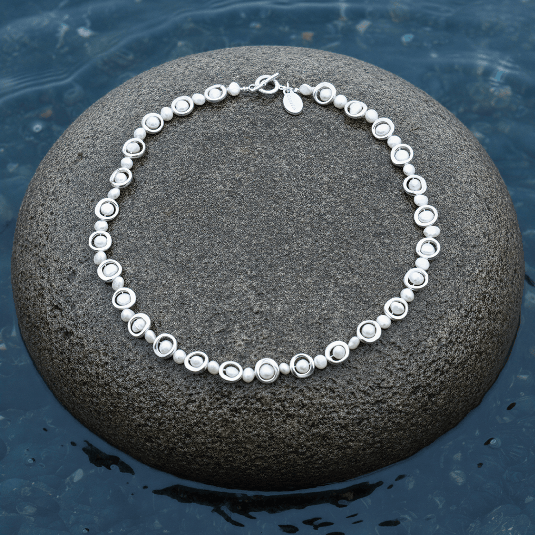 Zoetwater parelketting Pearl Geometric op steen blauwe waterrand bewolkte dag
