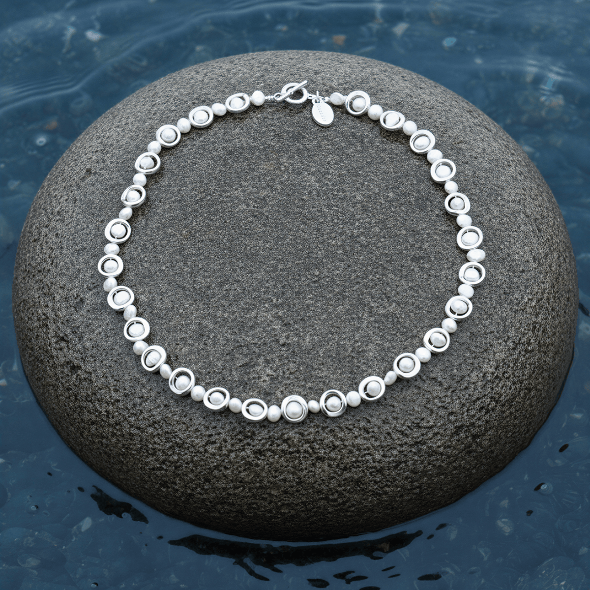 Zoetwater parelketting Pearl Geometric op steen blauwe waterrand bewolkte dag