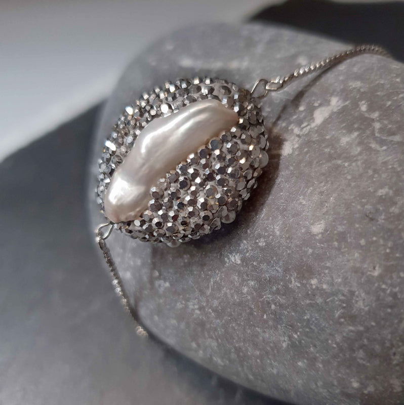 Wit zoetwater parel armband met stras steentjes, glitter armband met parel en schuifsluiting liggend op kei | Bright Biwa Silver