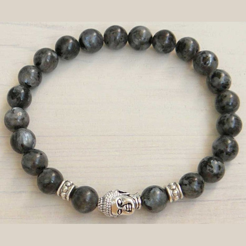 Edelstenen armband met zwarte edelstenen en een Boeddha hoofd liggend op plank | Elastisch | Buddha Larvikite