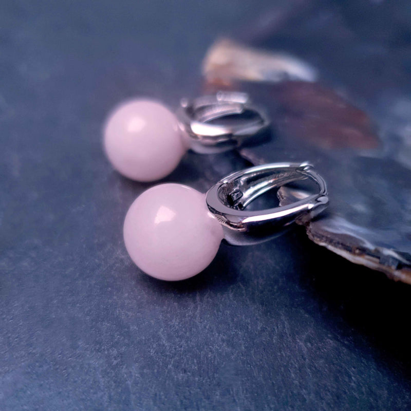 Roze edelstenen oorringen met rozenkwarts liggend tegen schelp | Silver Rosé Quartz Ball
