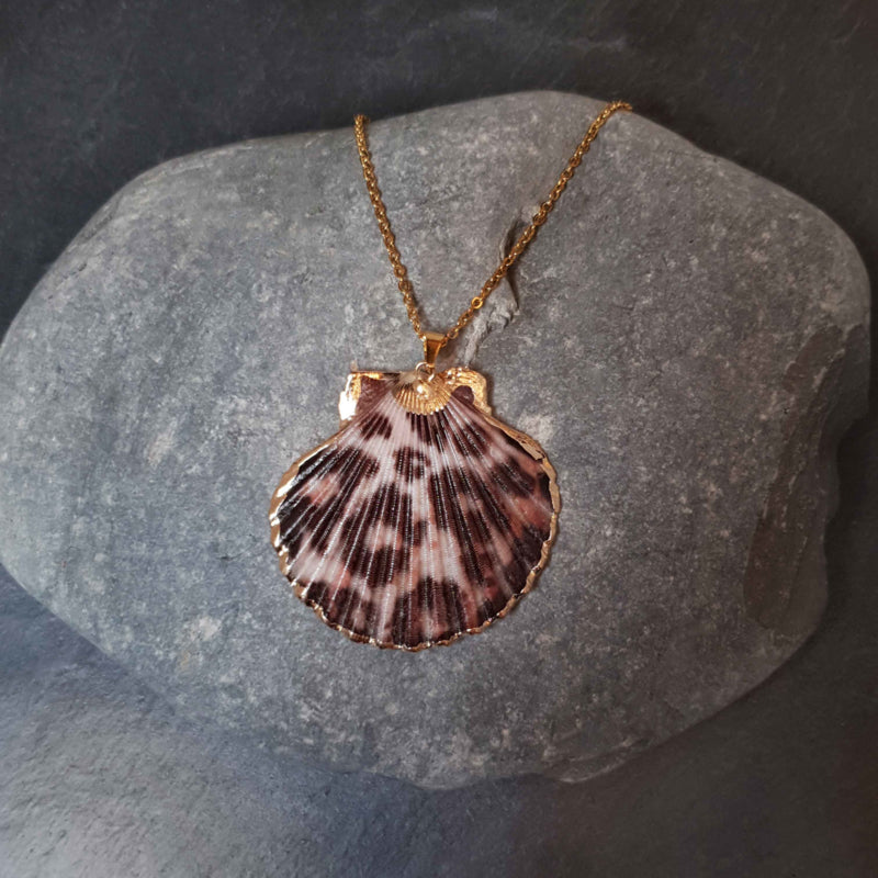 Detail van schelpen ketting met shell schelp en goud edelstaal liggend op kei | Gold Sea Shel Panther
