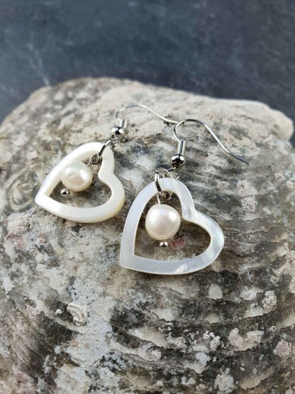 Witte zoetwater parel oorbellen met witte parel en parelmoer hart en sterling zilver (925) liggend op schelp | Pearl Heart Shell