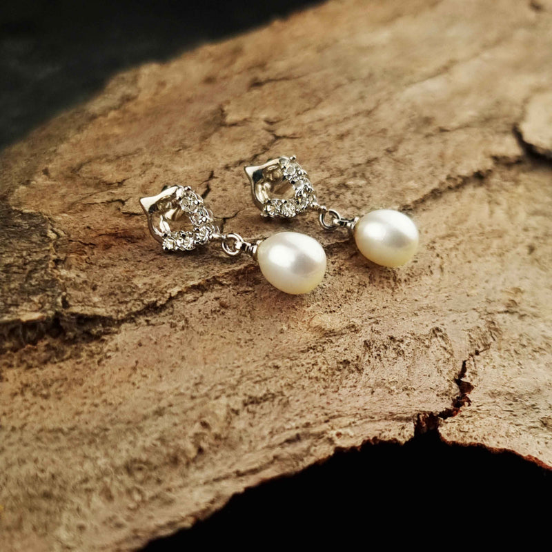 Witte zoetwater parel oorbellen met stras steentjes liggend op hout | Bling Pearl Heart W