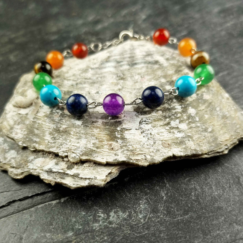 Edelstenen armband met veel gekleurde edelstenen| regenboog armband | Chakra armband liggend op schelp | Gemma