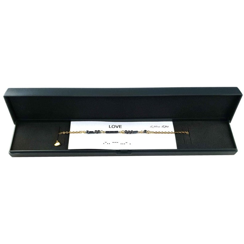 Zwarte edelstenen ketting met goud edelstaal en hematiet stenen die het woord LOVE in morse code weer geeft liggend in sieraden doosje | Morse Code Love Black Hematite Gold