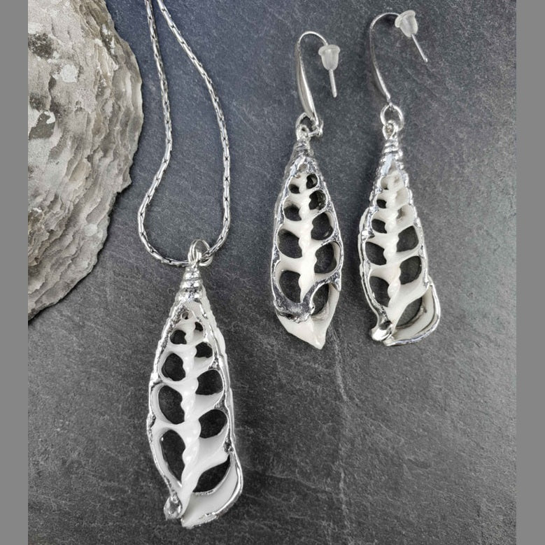 Schelpen sieraden set bestaande uit schelpen ketting en schelpen oorbellen met witte schelp en zilver edelstaal liggend op leisteen | set White Trumpet Shell Silver