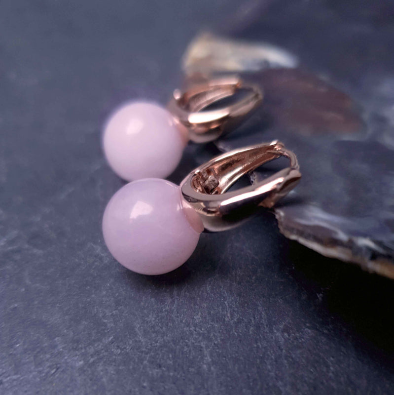 Roze edelstenen oorbellen met rozenkwarts en rose goud liggend tegen schelprand | Rose Gold Rose Quartz Ball