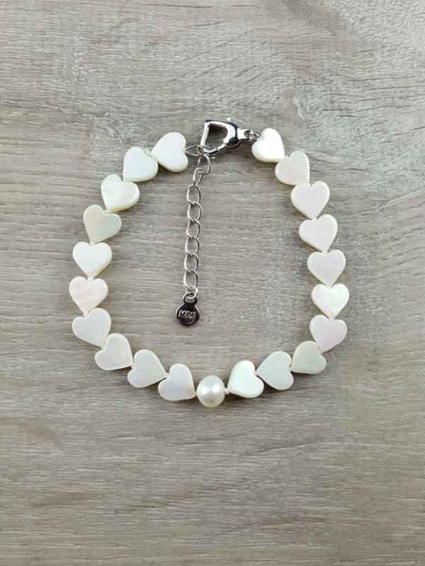Wit zoetwater parel armband met witte parelmoeren hartjes liggend op houten ondergrond | White Pearl Heart Shell