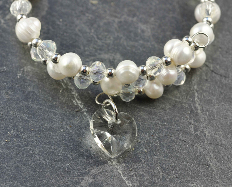 Detail van wit zoetwater parel wikkel armband met kristallen hartje liggend op leisteen | Wrap Pearl Crystal Heart