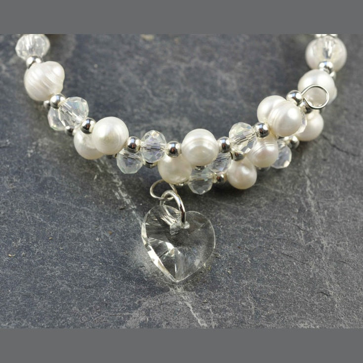 Detail van wit zoetwater parel wikkel armband met kristallen hartje liggend op leisteen | Wrap Pearl Crystal Heart