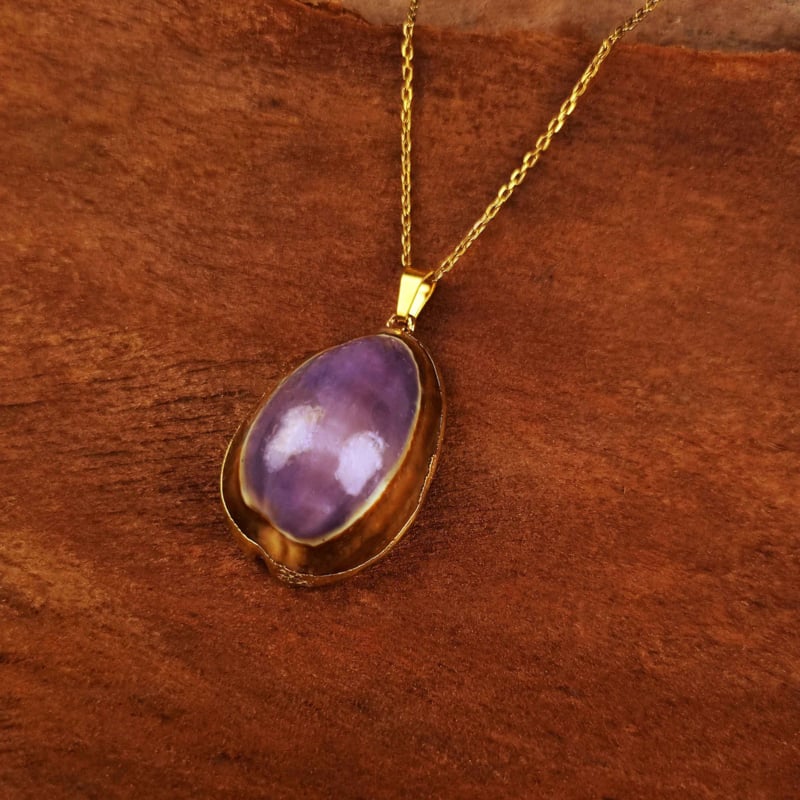 Paarse schelpenketting met goud edelstalen ketting liggend op hout | Shell Cowrie Purple