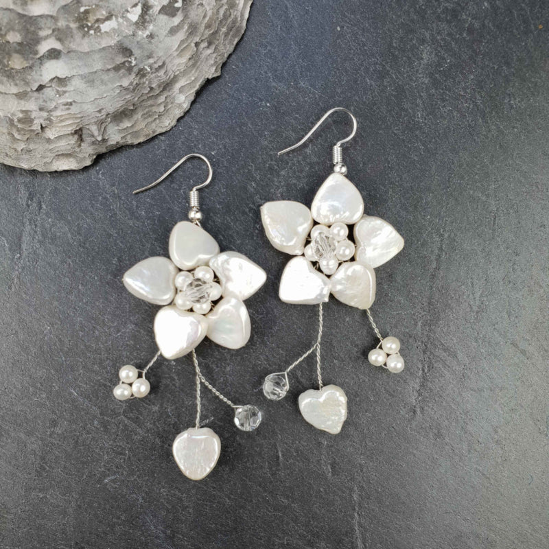 Lange zoetwater parel oorbellen met witte parels in bloem motief en sterling zilver (925) liggend op leisteen | Long White Flower Pearl